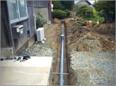 写真：排水設備工事で家の脇に溝を掘って地面に配管を通す様子